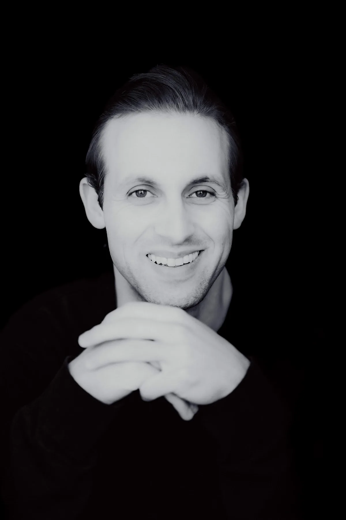 Portrait de Gabriel Stern, souriant, les mains jointes sous le menton